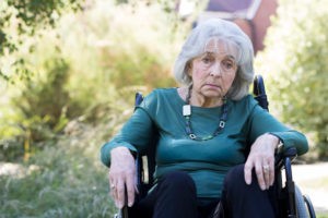 a sad older woman sitting in a wheelchair