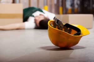 close-up on construction helmet on the ground with a worker on the floor