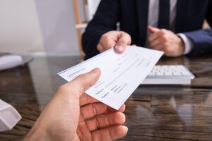 Close-up of a businessman's hand giving a check